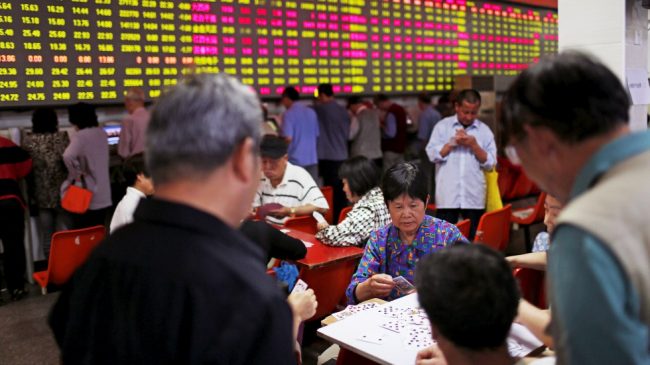 Chinese investors play cards while watching prices on the Shanghai Stock Market. Image credit: Reuters