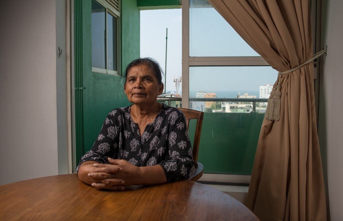 Kumala sits at the table in her living room, with an unspoiled view of the sea behind her. Image credit: Roar.lk/Christian Hutter