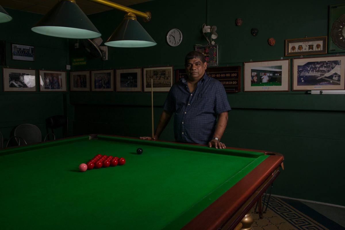 Noor stands at the billiard table, on the second floor of the Cue Club in Slave Island. Playing billiards or snooker has been a tradition in his family for more than a hundred years. Image credit: Roar.lk/Christian Hutter