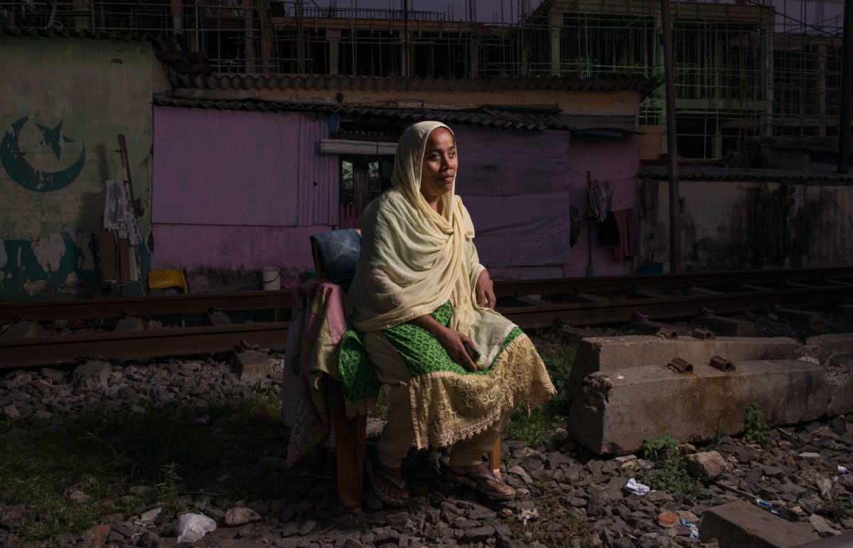 Nona sits on a plastic chair, in between the railway tracks that border her house. Image credit: Roar.lk/Christian Hutter