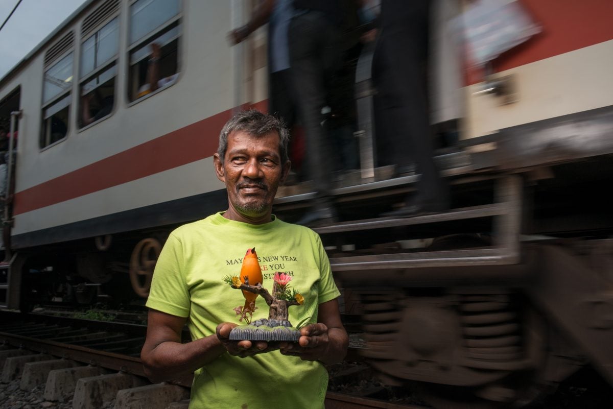 Portrait of Mr. Faleel and his bird statue. He insisted that he hold it when posing for the photograph in front of the railway tracks at Slave Island. Image credit: Roar.lk/Christian Hutter 