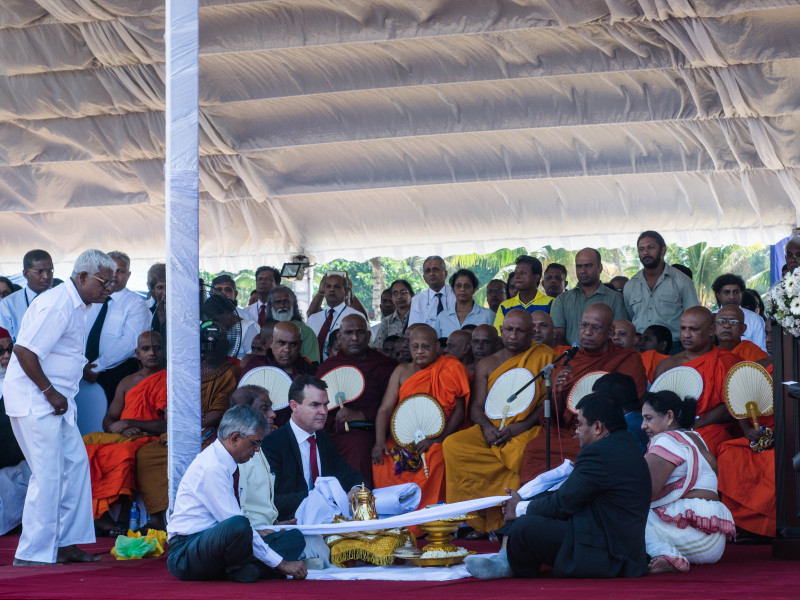 Minister of Sustainable Development and Wildlife, Gamini Jayawickrama Perera, Minister of Finance, Ravi Karunanayake, and Secretary-General for the Convention on International Trade in Endangered Species (CITES), John Scanlon, are seen observing a Buddhist religious ceremony. Clergymen representing all religions were present, and each recited a prayer in memory of the butchered elephants.