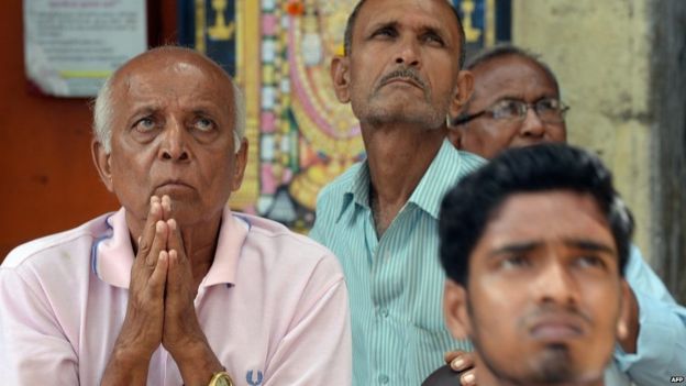 A group of men closely watching the stock market in Mumbai, India. Image Credit: BBC